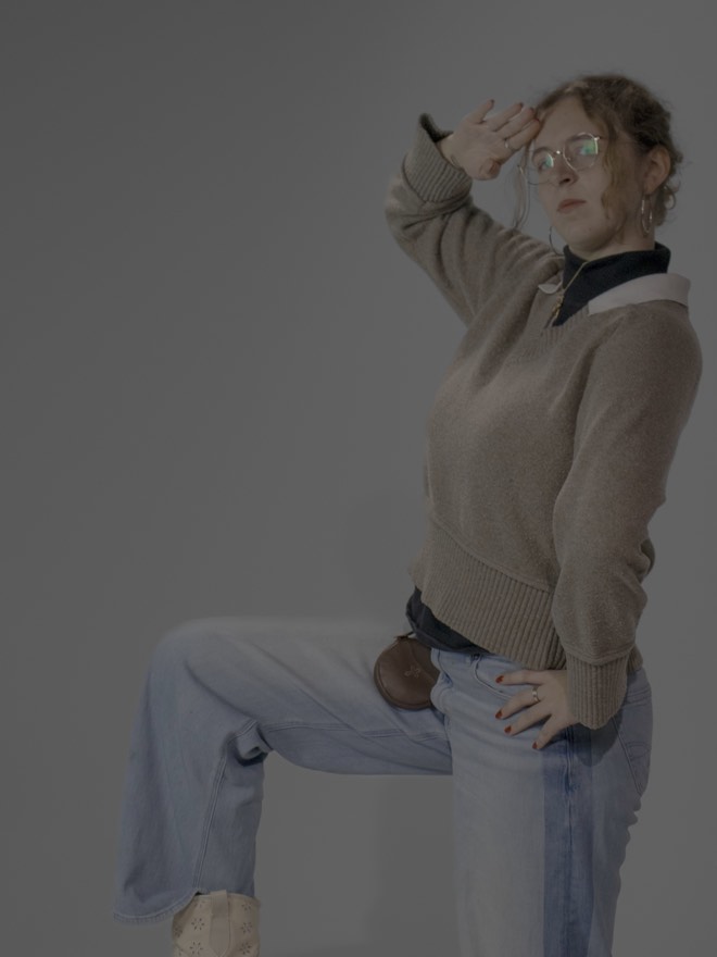 Mallory with one foot raised and a hand shading her eyes, looking into the distance